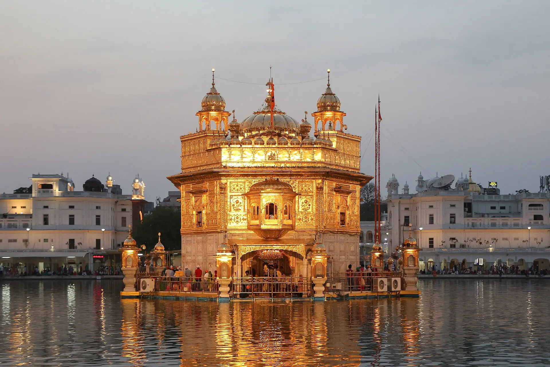 The Golden Temple glowing gold at dusk, reflected in the surrounding sarovar