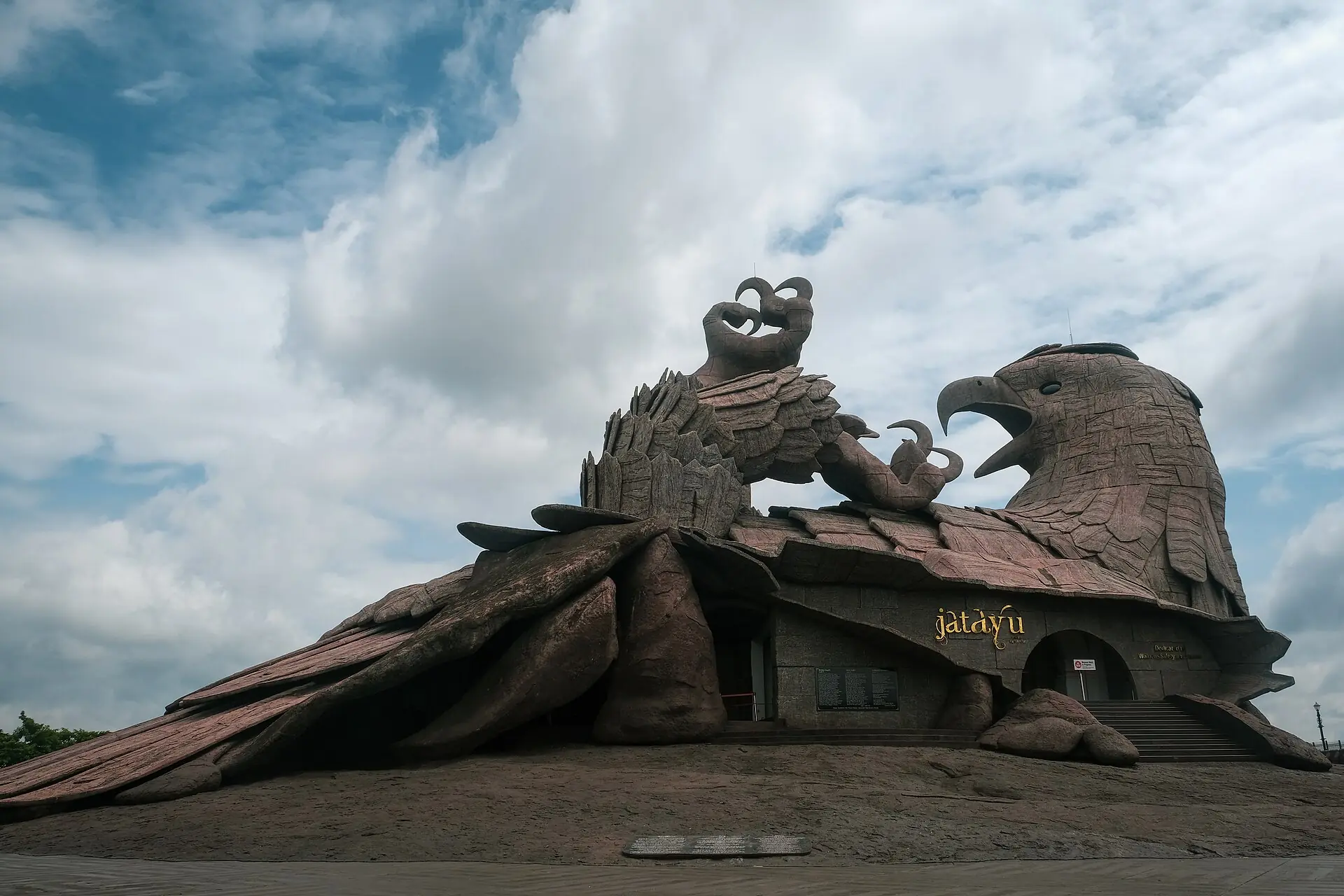 The giant stone Jatayu bird sculpture at Jatayu Earth's Center under clouds